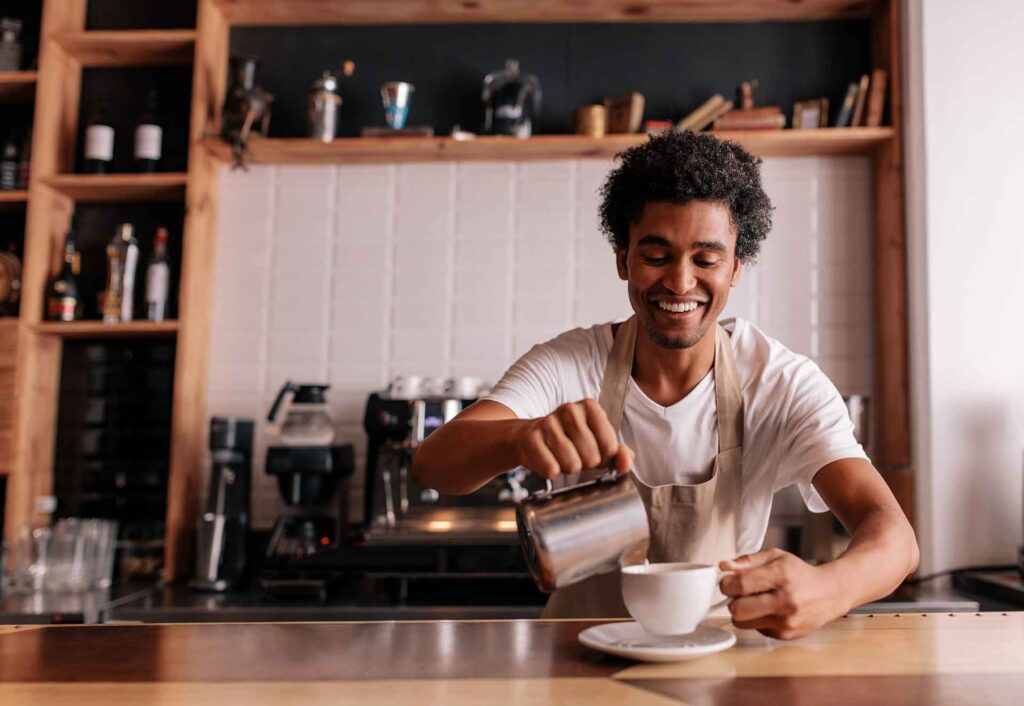 Barista gießt frisch zubereiteten Kaffee in eine Tasse im Café
